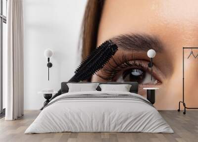 Young woman putting eye liner on eyelid on white background Wall mural